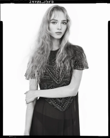 Black and white portrait of a female model wearing an embellished short-sleeve dress against a plain white background.