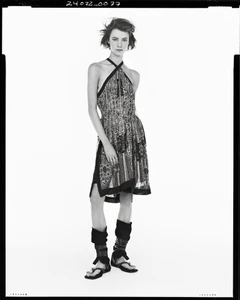 Model wearing patterned halter dress and strappy sandals against a white seamless background