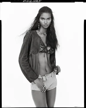 Monochrome portrait of a model in embroidered shorts, bralette, and jacket against a plain white background.