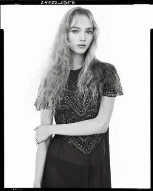Black and white portrait of a female model wearing an embellished short-sleeve dress against a plain white background.