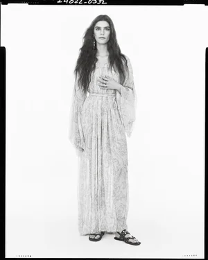 Model standing in a long patterned dress against a white background for Zara Studio S/S 2025 Campaign