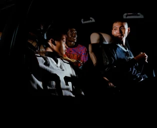 Three models inside a car at night featuring low-key lighting for Adidas Adilenium SS25 campaign by Ewen Spencer.