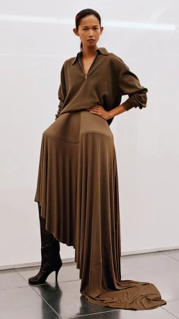 Model wearing a brown zip-collar top and long flared skirt against a white background