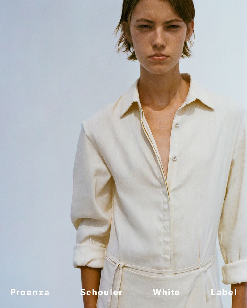 Model in a cream-colored jumpsuit by Proenza Schouler, showcasing white label fashion against a minimalist backdrop, portrait shot.