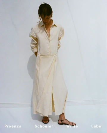 Model standing against a plain white background wearing a long cream button-down dress and black sandals for Proenza Schouler.