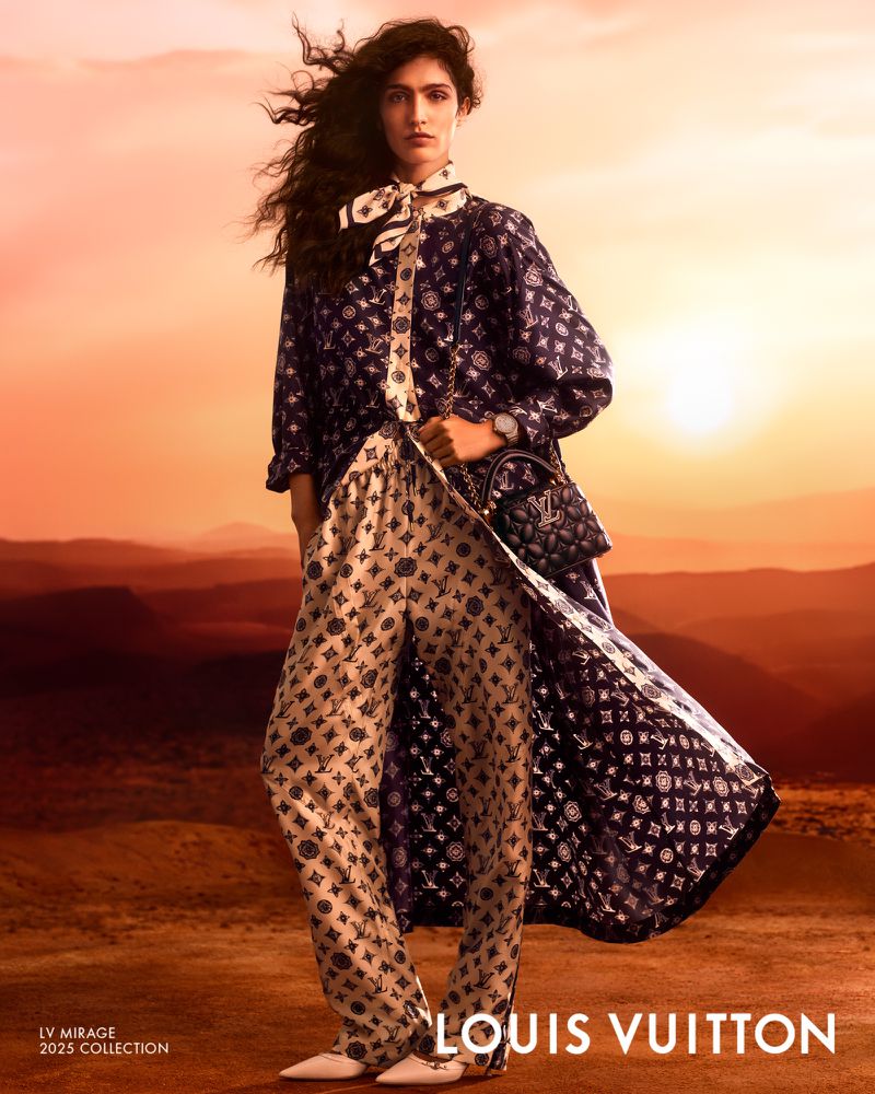 Fashion editorial shot of a woman in patterned top and pants, accessorized with a scarf and purse, set against an orange-toned desert backdrop.