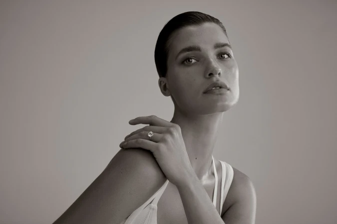 Close-up studio portrait of a woman with short dark hair wearing a ring. Soft lighting and neutral background emphasize the subject's features.