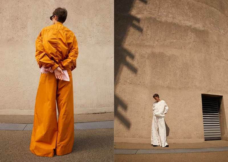Two images show a slender person posing in an outdoor setting wearing wide-leg pants and a matching jacket against a textured wall.