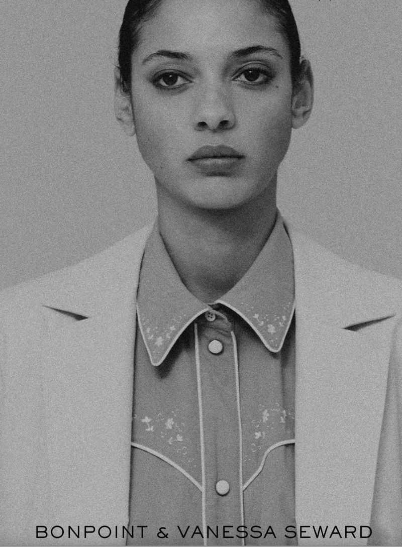 Monochromatic portrait of a woman in a light-colored blazer and western-style collared shirt, with visible text at the bottom of the image.