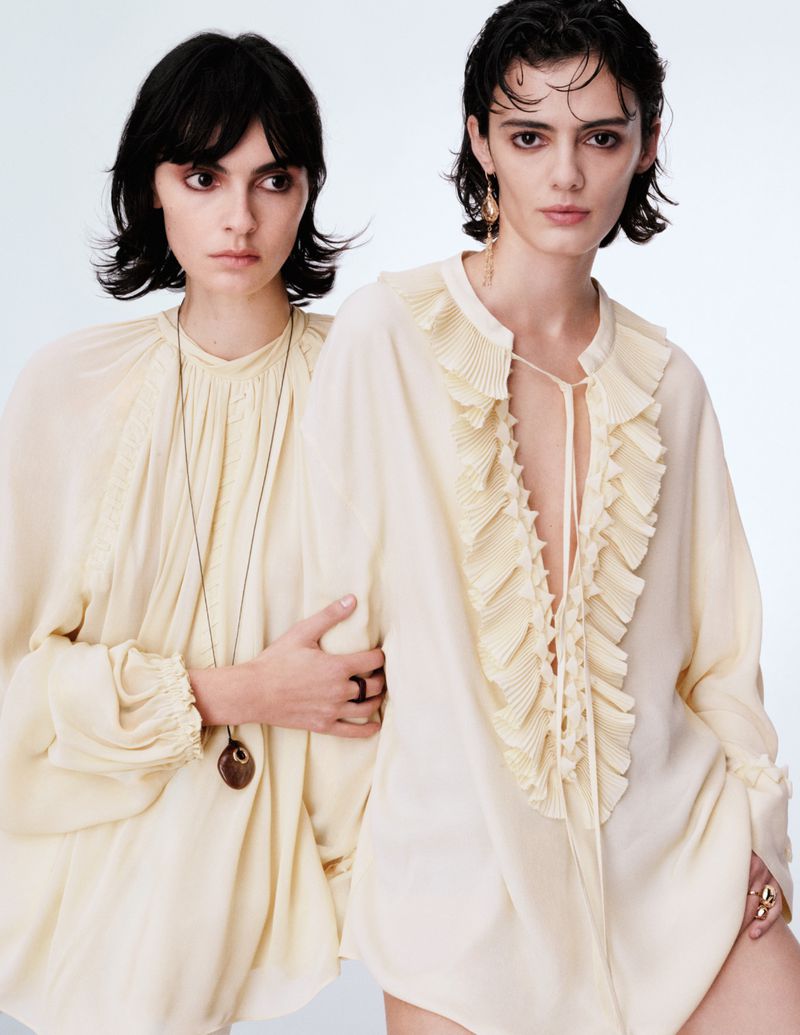 Two female models wearing cream ruffled tunics against a plain white studio background for H&M Ethereal Bohemia campaign