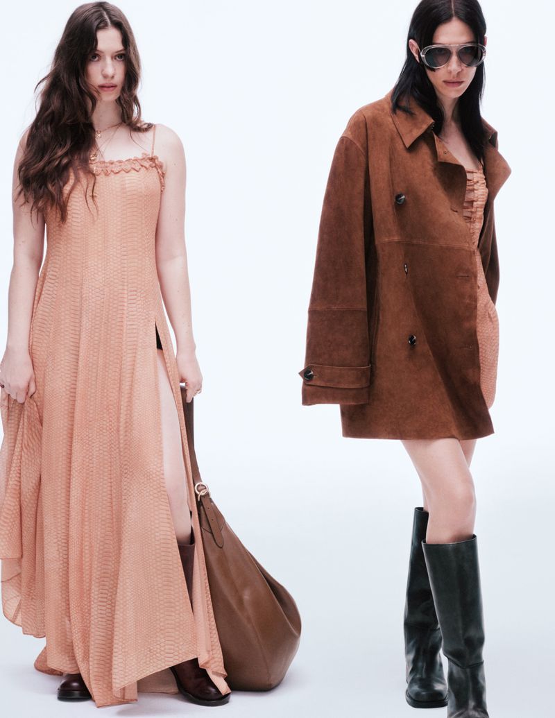Two adult women model contemporary fashion in a bright photo studio, one wearing a long brown dress and boots, the other a brown coat.