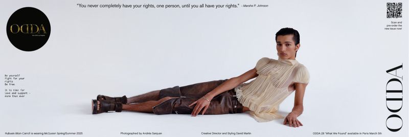 Fashion editorial image featuring a male model lying on a white background, wearing a tan top and brown shorts. 