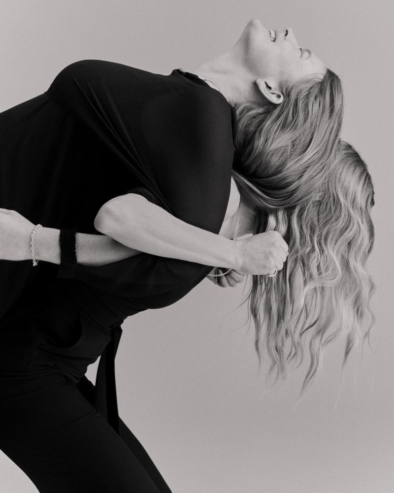 Monochrome image featuring two adult women in close embrace; one in black top and pants, the other with long blonde hair.