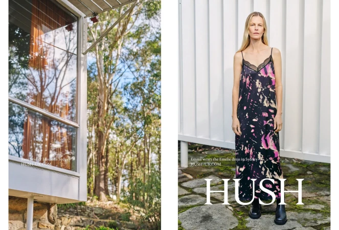 Fashion shot of a blond woman in a print dress, standing in front of a white wall with a tree-filled landscape to the left.