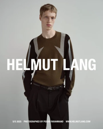 Model in brown patterned sweater and black trousers posing against a grey seamless studio backdrop for Helmut Lang