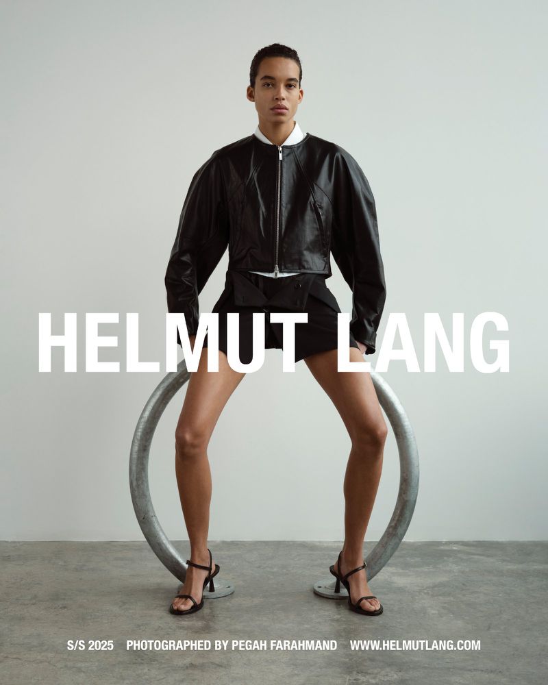 Fashion shot of a stylish adult posing indoors with a modern ring prop wearing a leather jacket, shorts, and high-heel shoes.