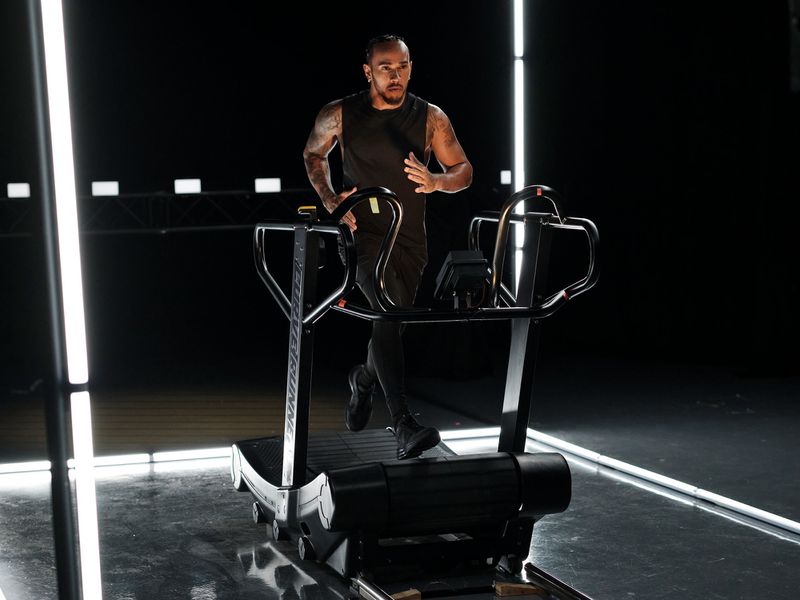 An adult male running on a treadmill in a studio setting, illuminated by neon lights, showcasing fitness and exercise in a modern, health-conscious scene.