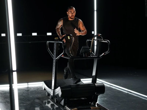An adult male running on a treadmill in a studio setting, illuminated by neon lights, showcasing fitness and exercise in a modern, health-conscious scene.