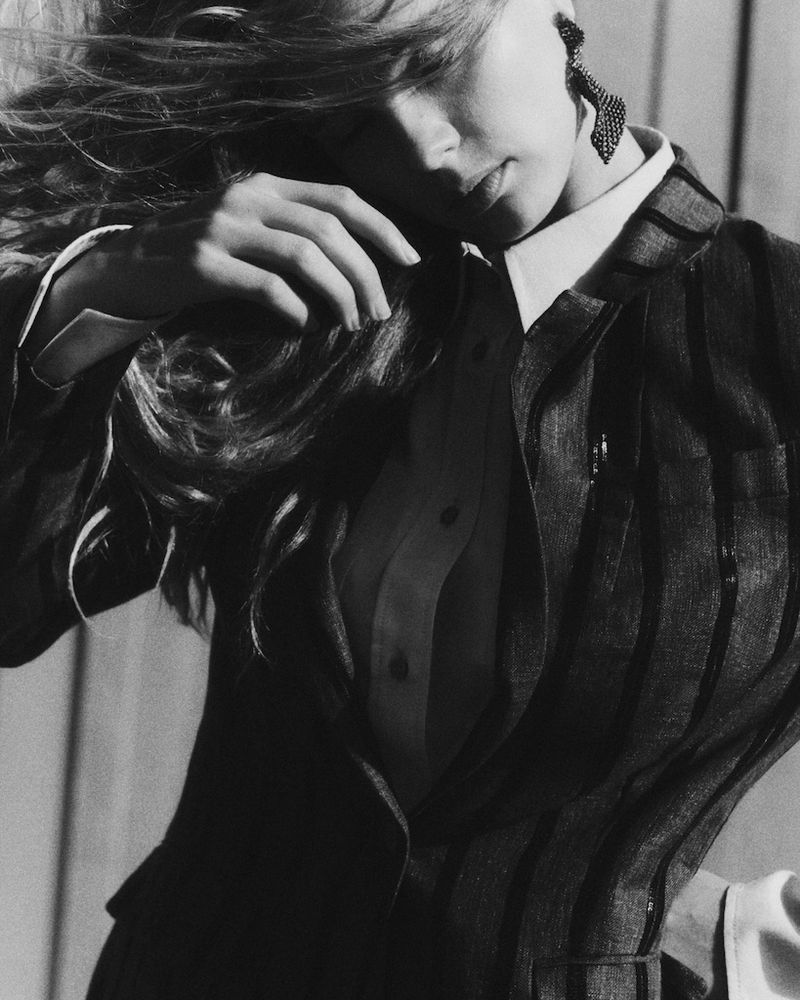 Monochrome fashion portrait of a model wearing a tailored jacket, white shirt, and statement earring