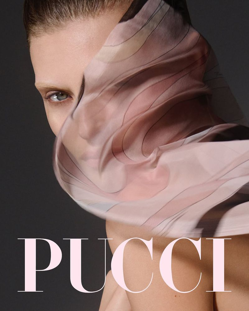 Close-up of a fashion model partially veiled with a patterned scarf against a gray backdrop, featuring the PUCCI logo in the foreground.