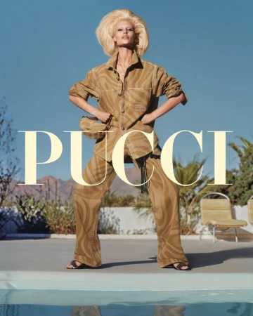 A woman in a brown patterned pantsuit poses in front of a pool and mountain landscape, accented by the large PUCCI logo overlay.