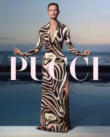 Elegant adult woman in a patterned dress strikes a pose in front of a pool at sunset. The brand name PUCCI is in foreground.