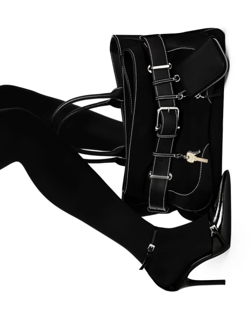 Black purse with silver hardware and black high heel shoes with ankle strap on an isolated white background in a studio shot.