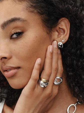 Close-up portrait of a model showcasing stacked silver and gold rings and matching earrings for Mejuri Art Of The Stack campaign.