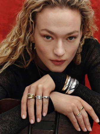 Close-up portrait of a woman wearing gold and silver jewelry including multiple rings and bracelets for Mejuri.