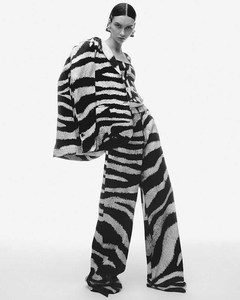 Woman in zebra-striped suit posing in studio. Fashion shot showcases a black-and-white patterned blazer and wide-leg pants on a model.