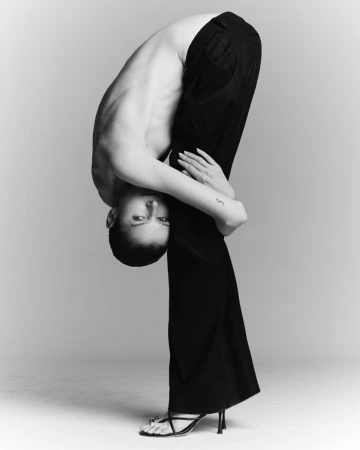 Model in black trousers bent completely backward against a grey background photographed by Emil Dietrich for Krobos 2025.