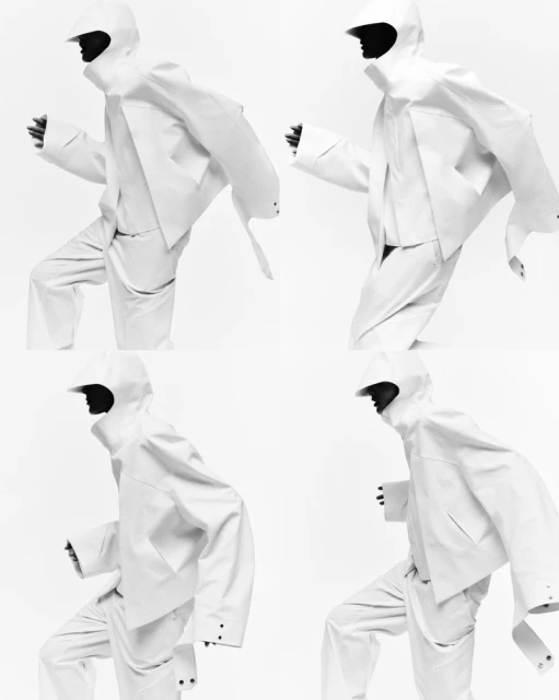 Four fashion models in white hooded outfits are striking a dynamic pose against a stark white background in a studio setting.