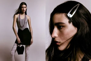Model in grey halter top and black skirt wearing white tights and holding heart bag against a grey backdrop