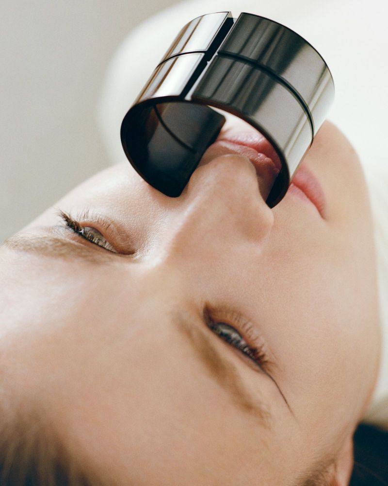 Close-up studio shot of a fair-skinned adult female with closed eyes, a large silver ring on her nose, set against a white background.