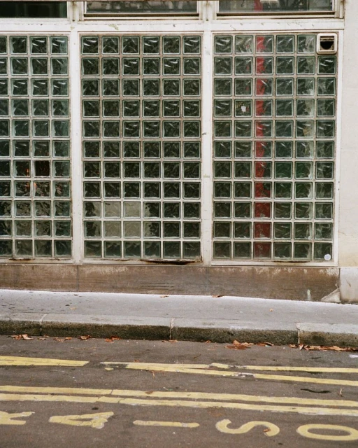 Exterior view of a building with a glass block facade and painted yellow lines on the street.
