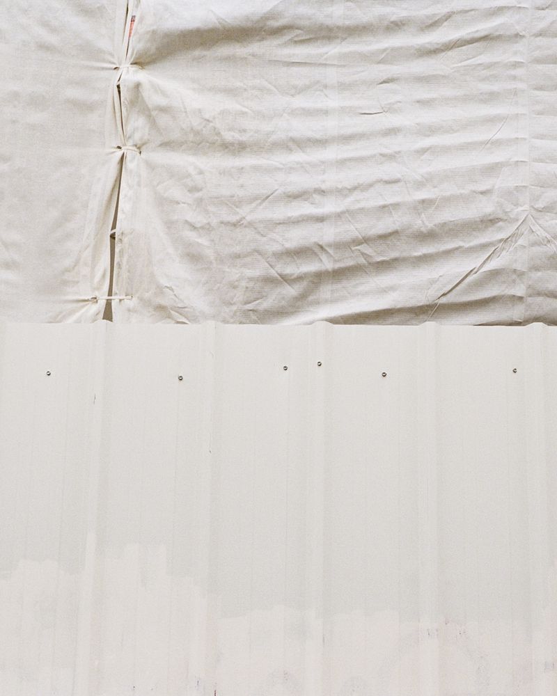 Close-up of a textured white canvas surface covering part of a white corrugated metal structure, showcasing its raw material.