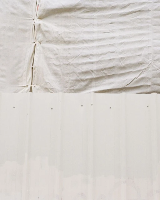 Close-up of a textured white canvas surface covering part of a white corrugated metal structure, showcasing its raw material.