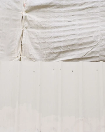 Close-up of a textured white canvas surface covering part of a white corrugated metal structure, showcasing its raw material.