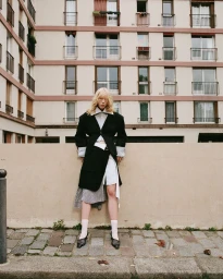 Model in layered black and white jacket standing against a building exterior in Re-Pull DROP 004