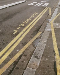 High angle shot of an asphalt street featuring yellow road markings and a curb