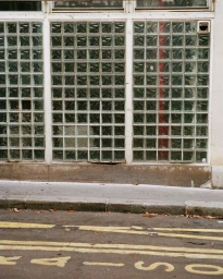 Glass block window facade above an asphalt street with yellow road markings and a curb
