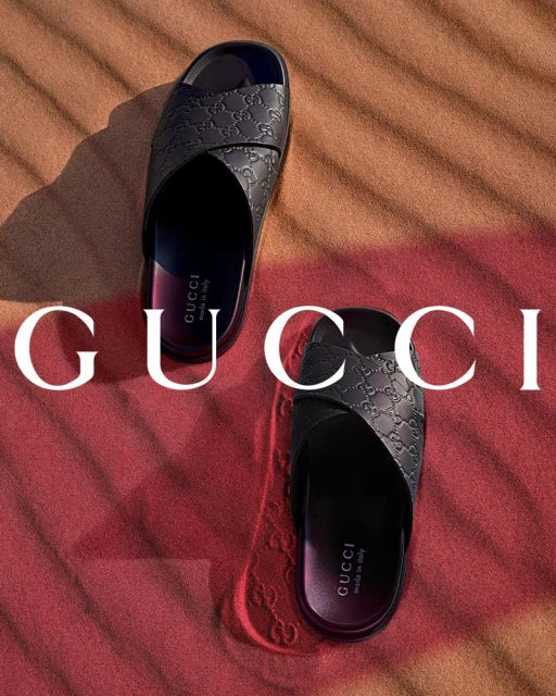 Gucci slide sandals on a tan and red background. Two stacked Gucci sandals, top and bottom, with logo printed on the background.