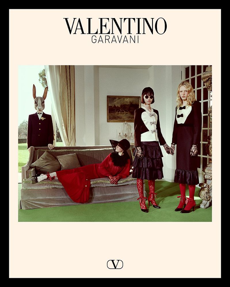 Valentino Garavani ad campaign in an ornate indoor setting. Models in formal attire, one with a rabbit head, lounge and pose.