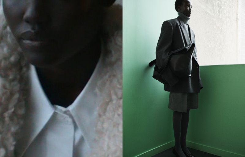 Dark-skinned model in gray suit poses indoors against a green and white wall; fashion editorial photography.