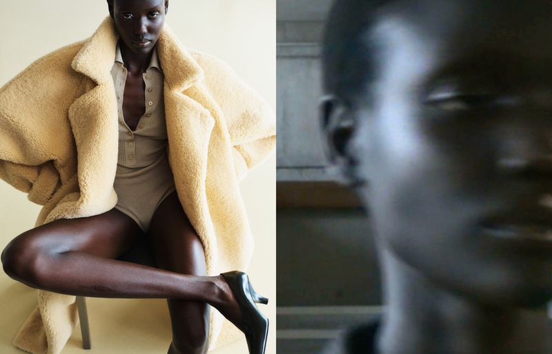 Editorial fashion shot of a dark-skinned model in a beige bodysuit and oversized coat, sitting in front of a split studio and natural environment background.
