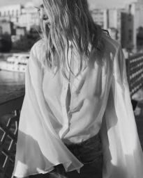 Monochrome fashion portrait of a model wearing a white blouse and dark trousers outdoors