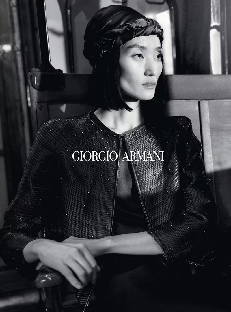 Black and white studio shot of an Asian female fashion model wearing Giorgio Armani jacket and headscarf, looking elegant and stylish.