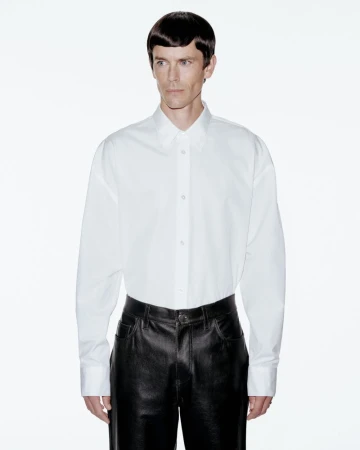 Model Jeremy Young wearing a white button-down shirt and black trousers against a plain white background for Berner Kühl