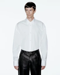 Model Jeremy Young wearing a white button-down shirt and black trousers against a plain white background for Berner Kühl