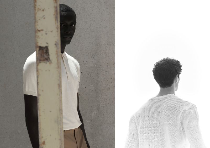 Two male models pose in soft, filtered light: one dark-skinned wearing a polo, the other fair-skinned with his back turned wearing a sweater.